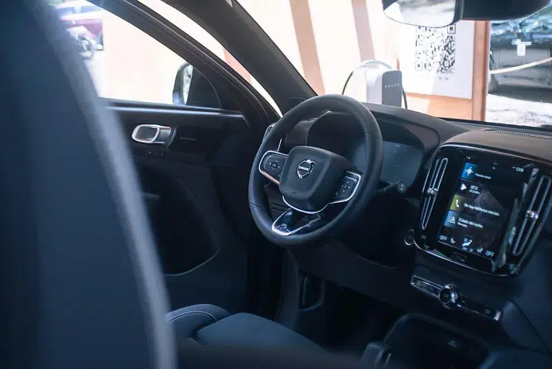 Close-up of a Volvo interior, featuring a leather-wrapped steering wheel, digital dashboard, and touchscreen infotainment system.
