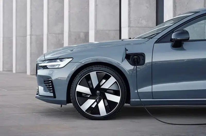 Side view of a Volvo plug-in hybrid sedan charging, highlighting its sleek design and modern alloy wheels.