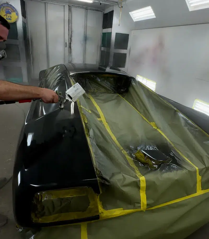 Technician refinishing Lamborghini Countach in a high-end paint booth