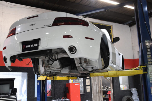 Rear View of Aston Martin V8 Vantage on Lift – European Auto Service Aston Martin V8 Vantage on hydraulic lift at Reseda auto repair workshop