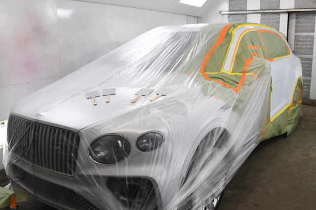 Bentley Bentayga Prepped for Paint Repair – European Auto Service Bentley Bentayga masked with plastic and tape inside a professional paint booth at European Auto Service in LA