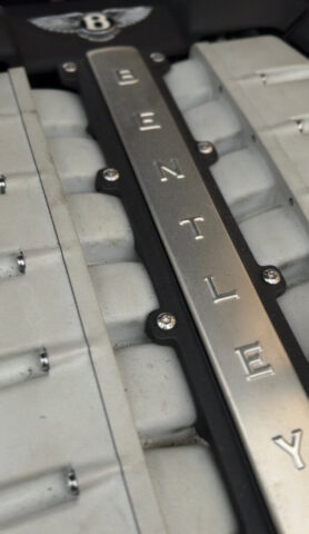 Close-Up of Bentley Engine Intake Cover with Logo Detailed view of a Bentley engine showing the metallic intake cover with Bentley logo and embossed lettering, captured during diagnostics at European Auto Service in LA