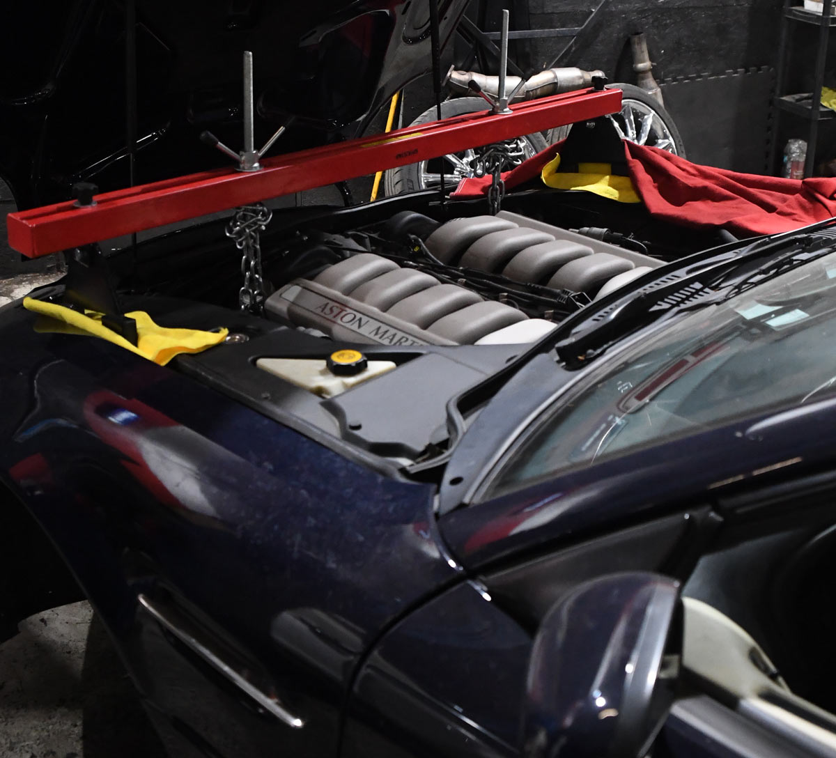 Aston Martin V12 engine with red support bar and protective covers during major engine service at European Auto Service