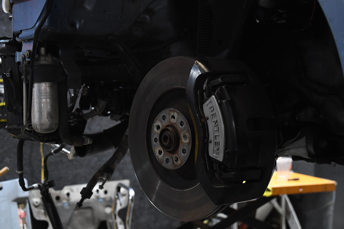 Bentley brake rotor with branded caliper and air suspension strut visible during service at European Auto Service