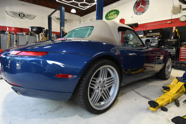 Rear quarter view of BMW Z8 with Alpina wheels at European Auto Service, Bentley and Land Rover logos on shop wall