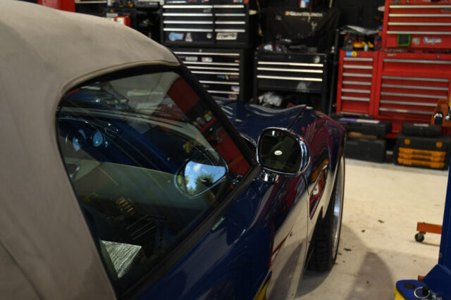 Blue BMW Z8 with tan soft top inside European Auto Service workshop, professional tool cabinets visible in background