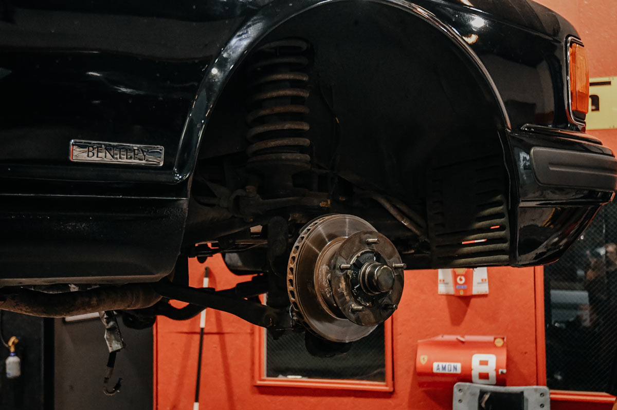 Classic Bentley on lift with wheel removed showing brake disc and hub assembly during inspection at our Reseda facility