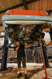 Two technicians carefully installing rebuilt engine into classic Lotus Esprit at European Auto Service