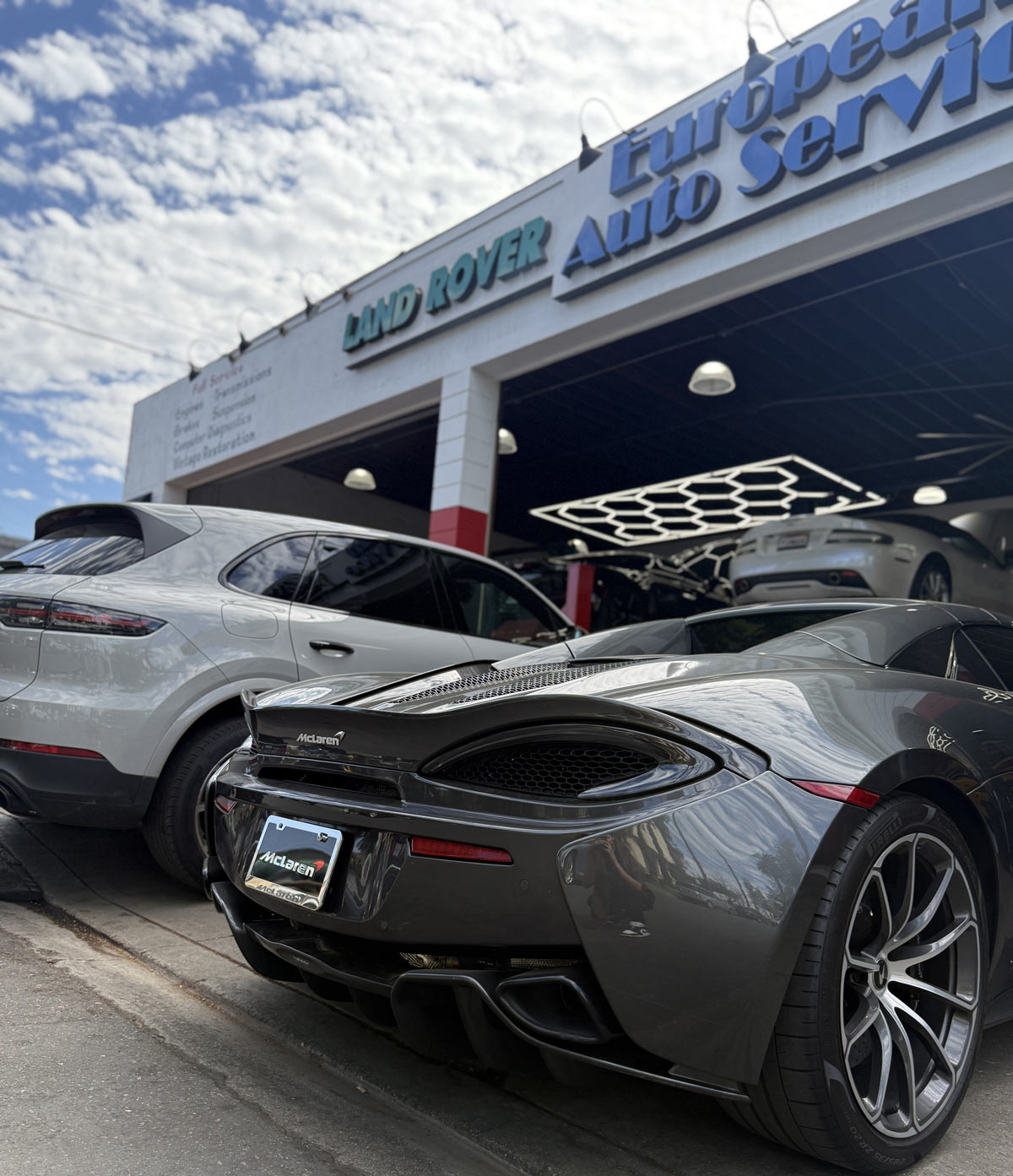 Gray McLaren 570S parked at European Auto Service storefront in Reseda with Land Rover signage visible