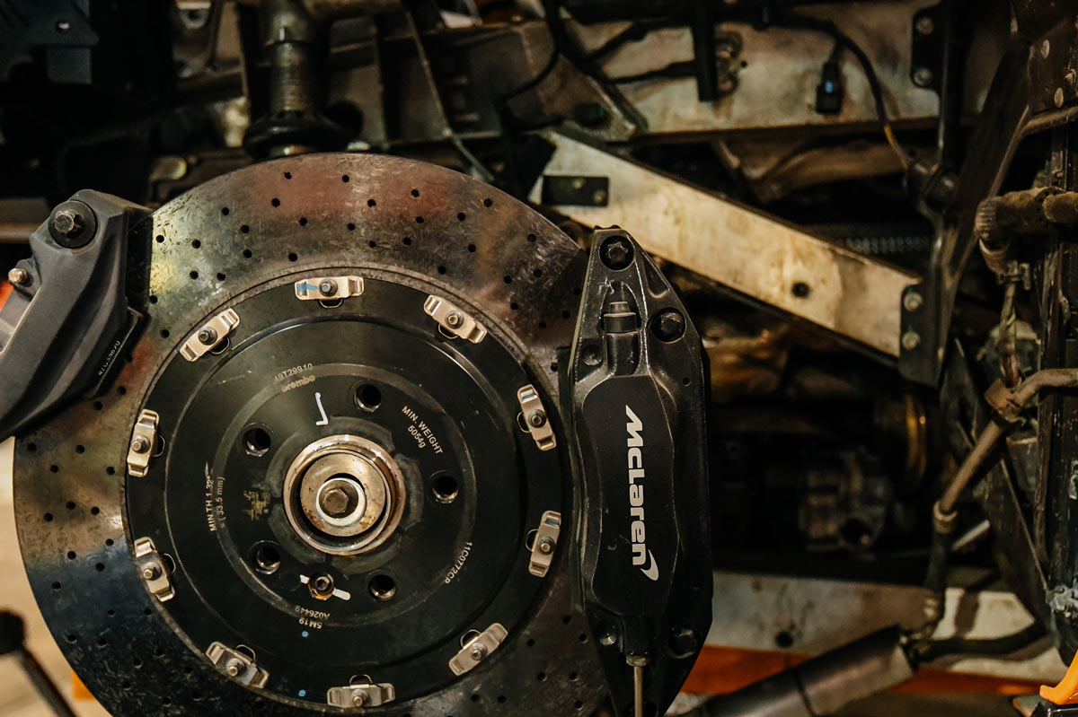 Close-up of McLaren drilled Brembo brake rotor and branded caliper during specialist brake service at European Auto Service