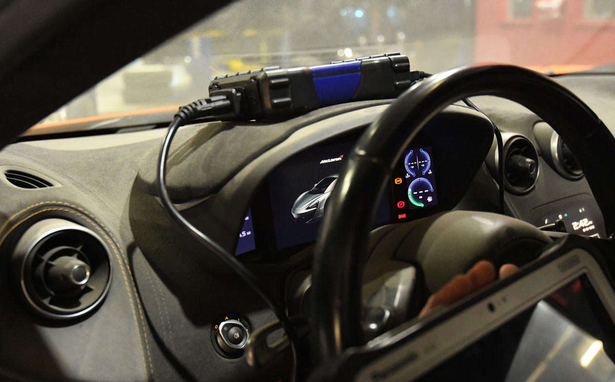 McLaren cockpit with OBD diagnostic connector plugged into dashboard showing instrument cluster during specialist diagnostics at European Auto Service