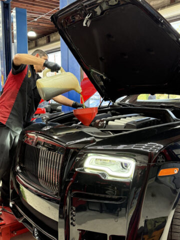 Certified technician performing oil change on black Rolls-Royce using Liqui Moly synthetic oil at European Auto Service Reseda