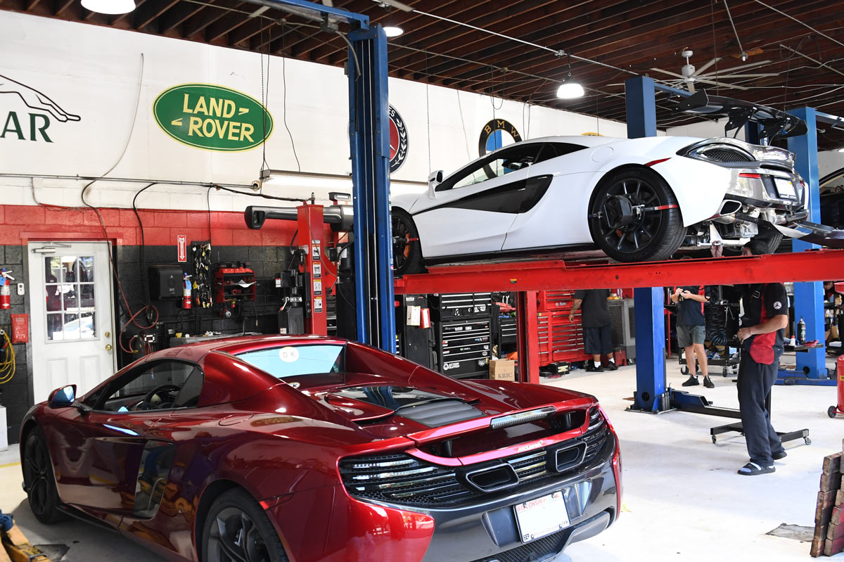 Red McLaren MP4-12C and white McLaren 570S on lift being serviced simultaneously at European Auto Service in Reseda