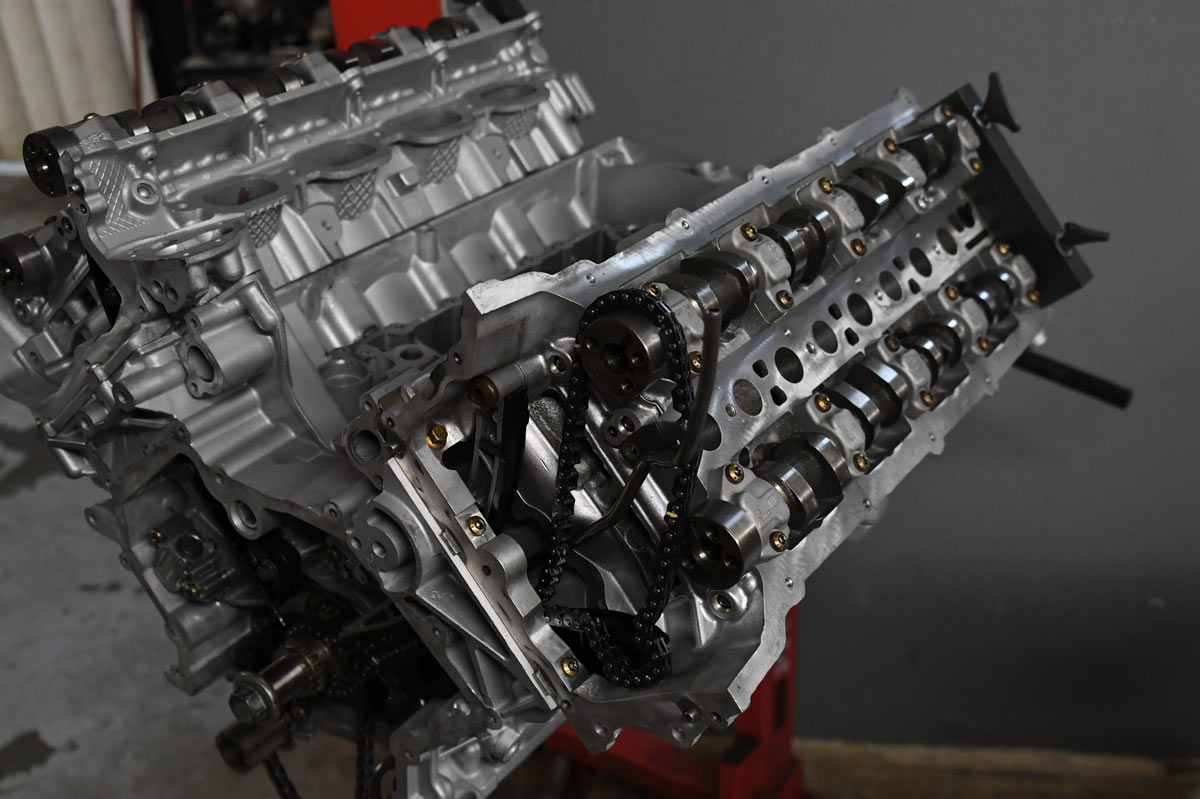 Rebuilt European V-engine with exposed timing chain and camshafts on engine stand at European Auto Service shop in Reseda