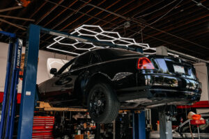 Black Rolls-Royce on Rotary Lift under hex LED lighting at European Auto Service facility in Reseda, Los Angeles
