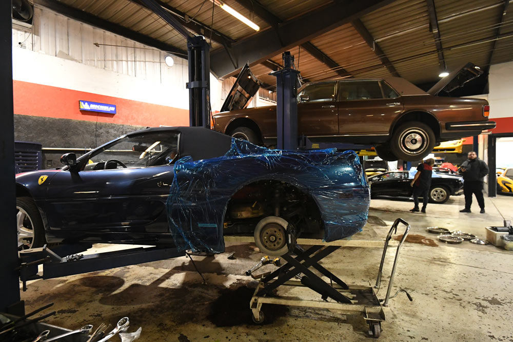 Ferrari F355 on scissor lift at European Auto Service in Reseda — second Ferrari and exotic vehicles visible in background