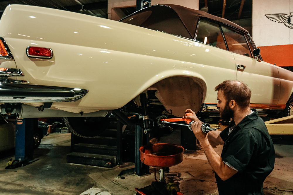 Mechanic replacing rear axle components on Mercedes 280SE Cabriolet