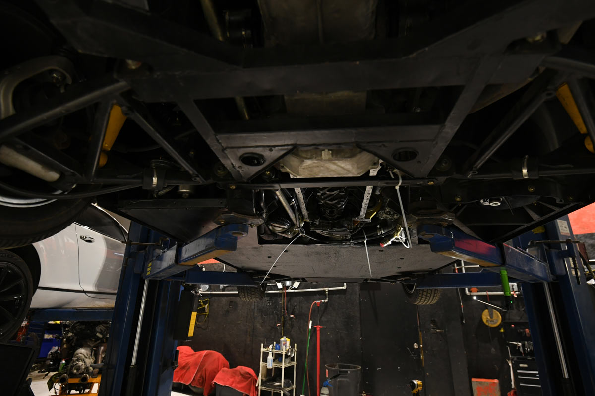 Technician inspecting BMW M1 undercarriage during engine-out service at European Auto Service in Reseda