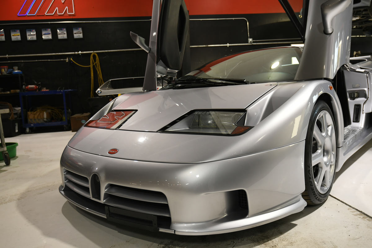 Silver Bugatti EB110 SuperSport with both scissor doors raised at European Auto Service in Reseda