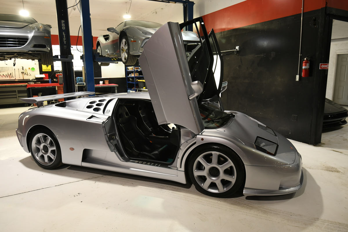 Bugatti EB110 SuperSport with both doors open beside Ferrari 612 on lift at European Auto Service Reseda