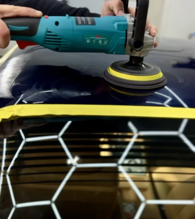Close-up of a car detailer using a power polisher to achieve a high-gloss finish